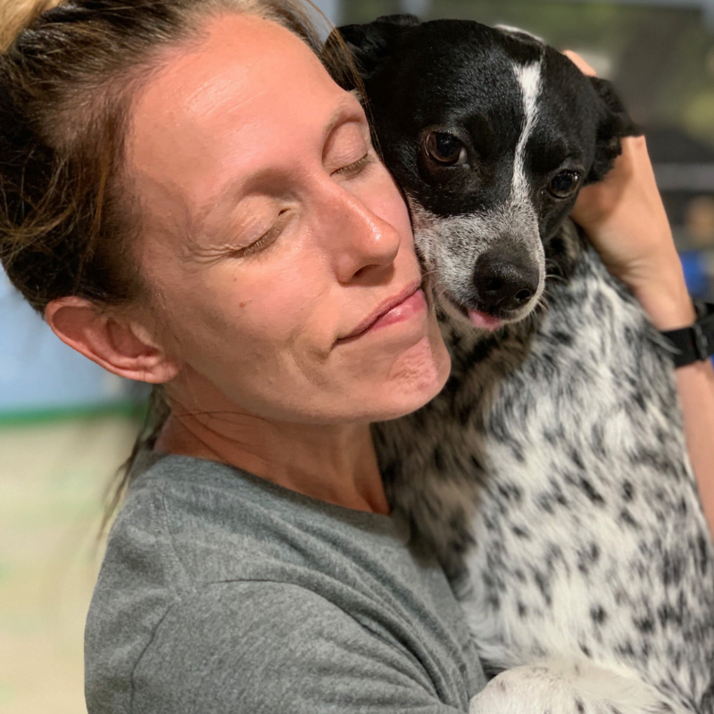 Rachel Hutcheson hugging small black and white dog